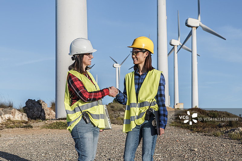 西班牙阿尔梅里亚风力发电场，两位女工程师正在讨论项目图片素材