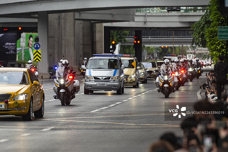 载有诗丽吉王太后遗体的车队庄严地驶过曼谷，由警察和官员护送，曼谷，泰国，市民向其致敬。图片素材