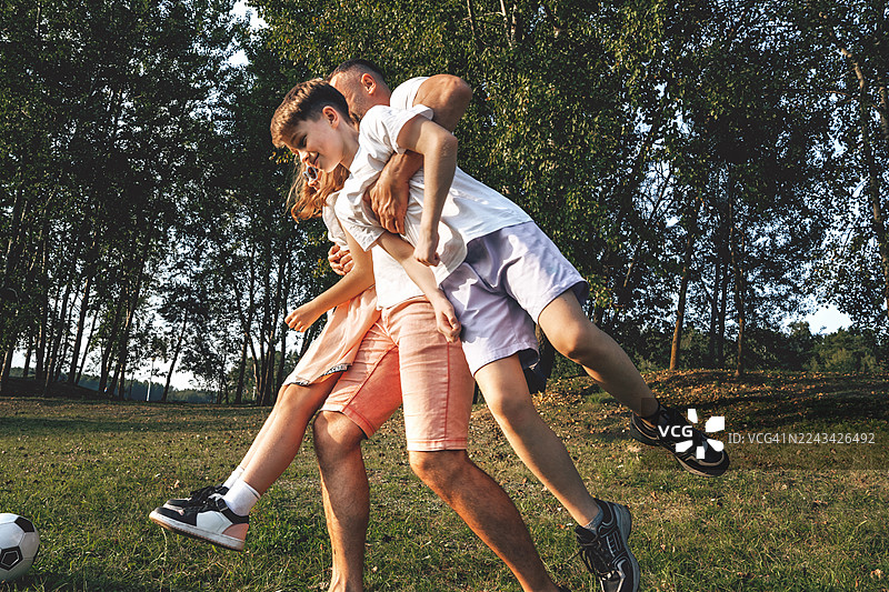 父亲在户外抱着他两个十几岁的孩子，玩得很开心。父爱图片素材