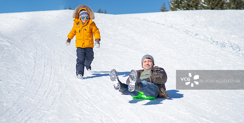 父亲和儿子在雪中玩耍——冬季户外乐趣图片素材