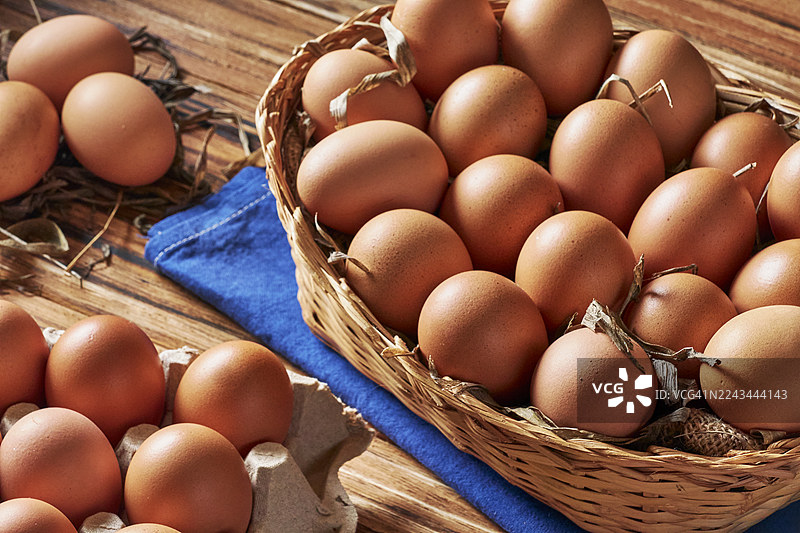 俯视角度拍摄的竹篮中新鲜鸡蛋放在质朴的木桌上图片素材