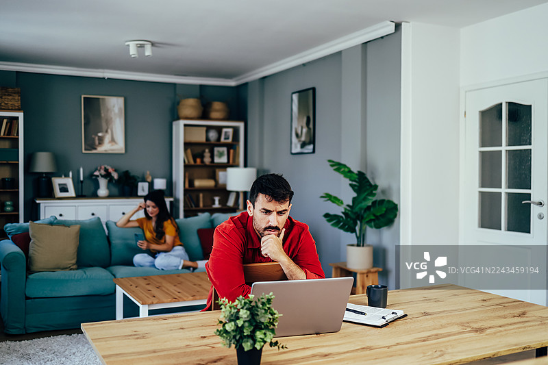 一对专注的情侣在家中的客厅远程工作图片素材