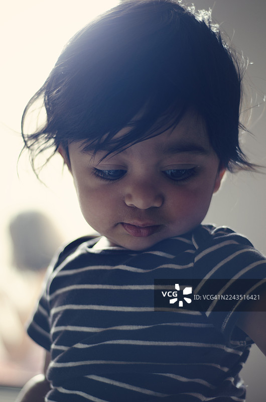 深度专注：蹒跚学步的孩子在柔和的光线下玩玩具。印度男童的特写肖像。图片素材