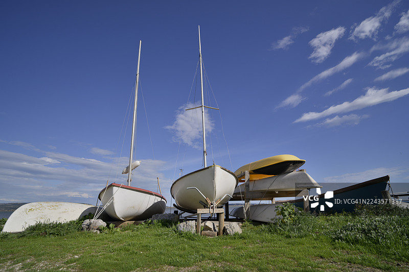 从低角度看，池塘边停泊着老旧的帆船图片素材
