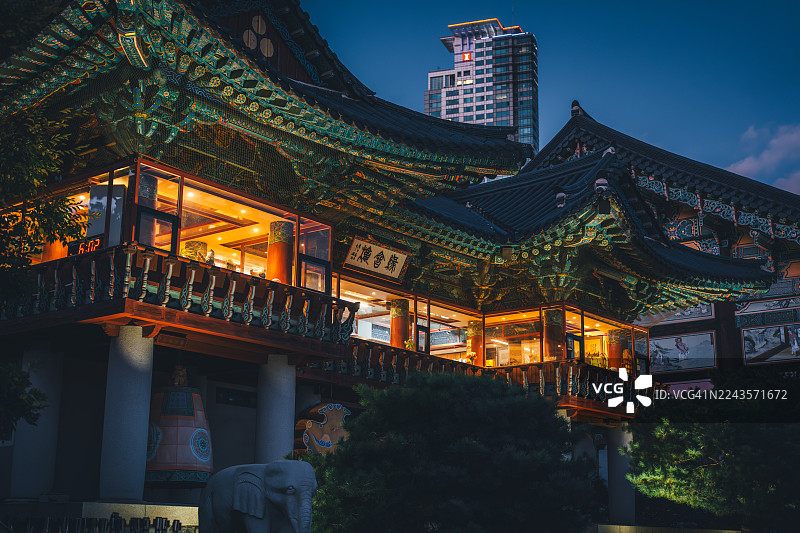 首尔韩国奉恩寺在暮色中与现代摩天大楼同框的景象图片素材
