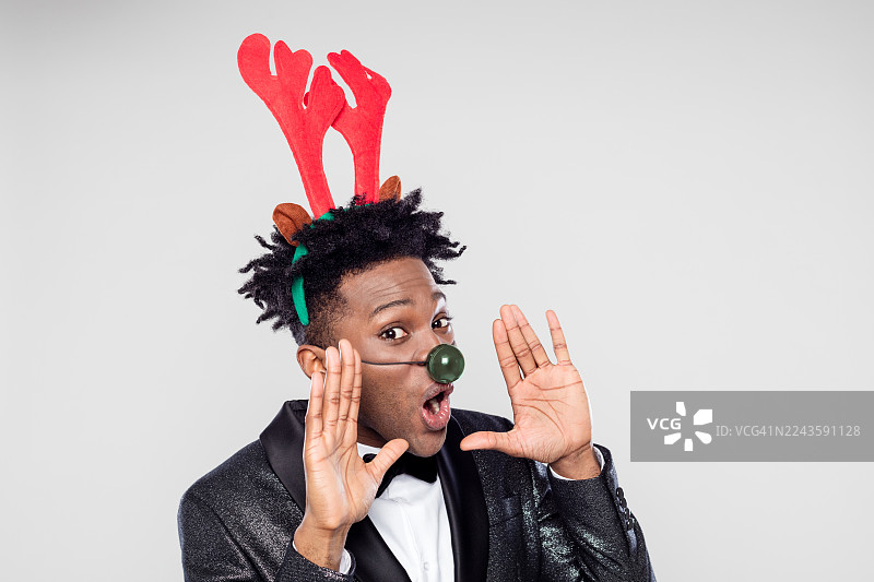 快乐优雅的男士戴着驯鹿头饰拍摄的搞笑圣诞肖像图片素材