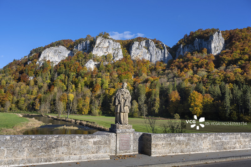 从历史悠久的拱桥,多瑙河上的豪森桥望去,桥上有圣约翰·内波穆克雕像,他是桥梁的守护神,身后是标志性的豪森峰、攀岩石、侏罗纪石灰岩悬崖、白侏罗纪岩石。图片素材