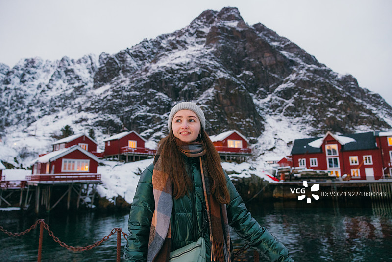 一位英俊的女士在渔村散步，背景是罗弗敦的红色罗布尔小屋图片素材