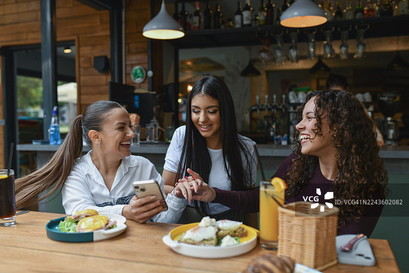朋友们在休息酒吧享用早餐，有说有笑，击掌庆祝图片素材