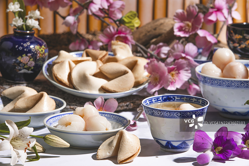 亚洲餐具中的荔枝、荔枝酒和幸运饼干，周围环绕着花朵图片素材