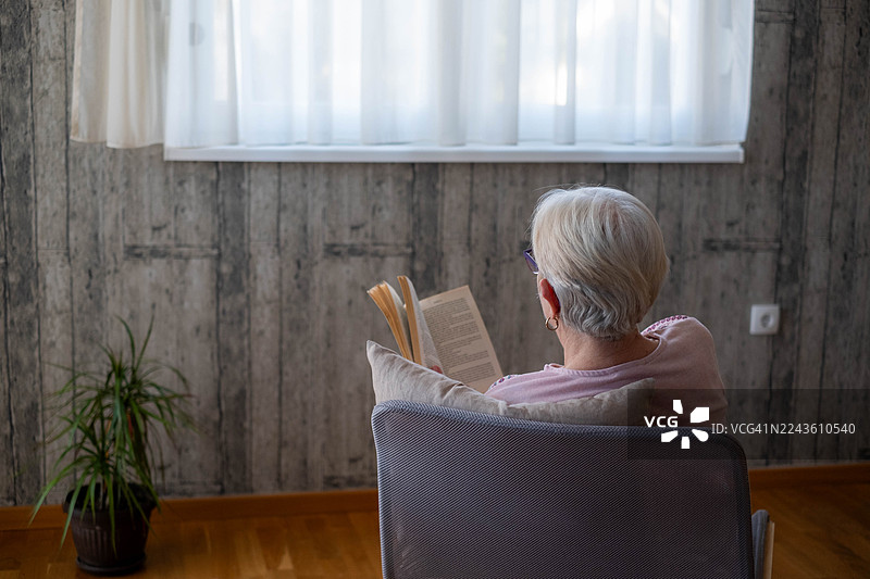 一位年长的女士在家中放松地阅读书籍图片素材