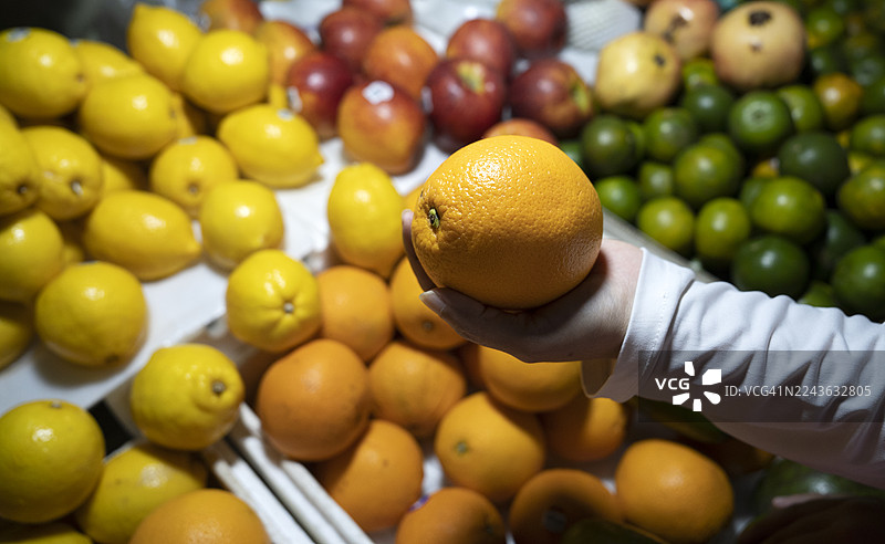 特写镜头：女人在超市手里拿着橙子图片素材