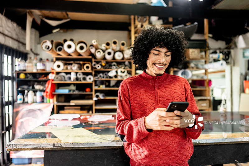印刷店里，一位中年男子微笑着查看手机图片素材