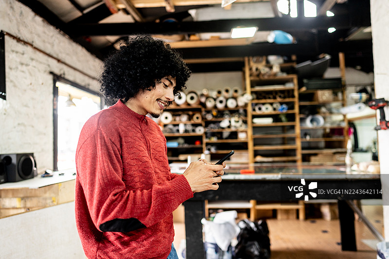 印刷店里，一位中年男子微笑着查看手机图片素材
