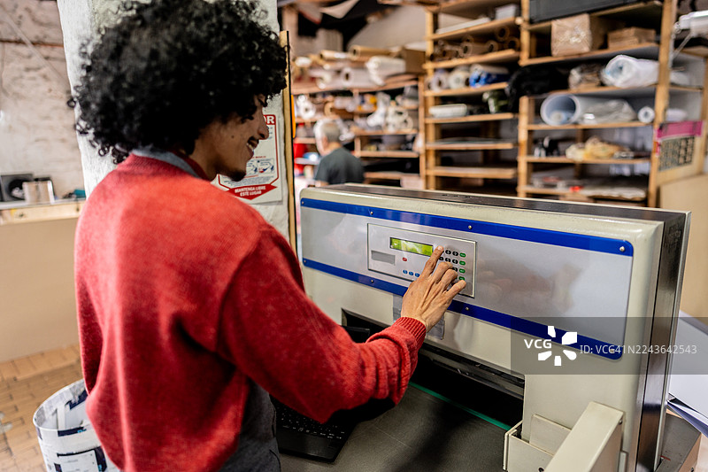 印刷店里操作数码印刷机的工人图片素材