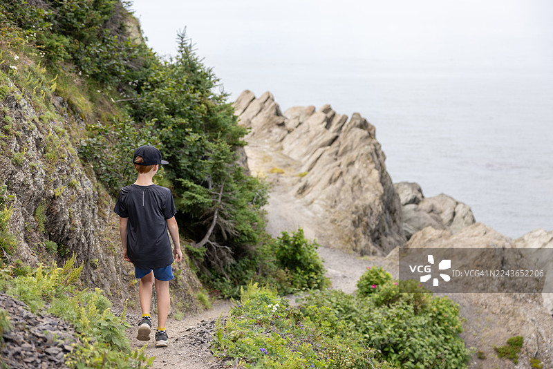 年轻的红发男孩在加拿大魁北克省Bic国家公园（Parc National du Bic）圣劳伦斯湾南部海岸徒步图片素材