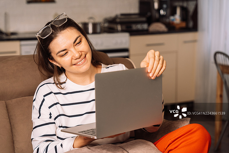 女人在沙发上对着笔记本电脑微笑图片素材