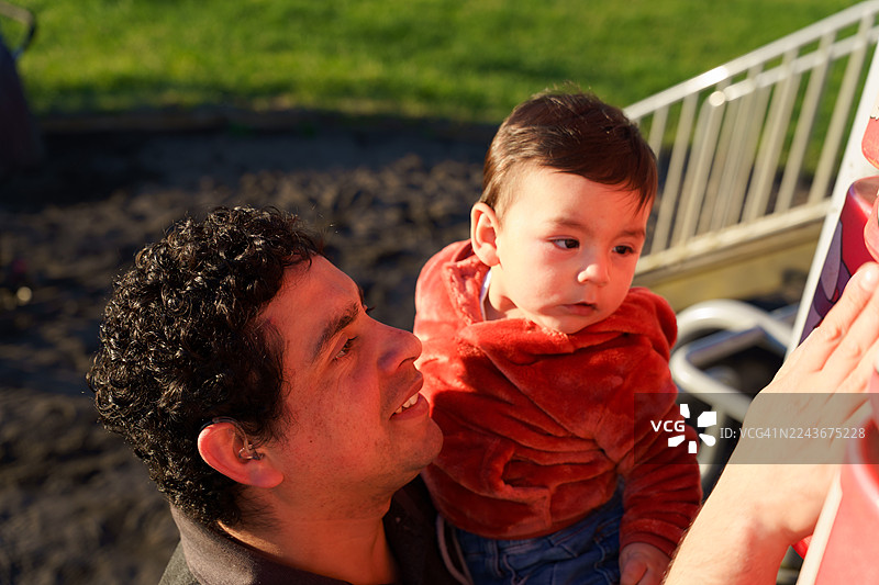 拉丁美洲的父亲和婴儿在游乐场玩耍图片素材