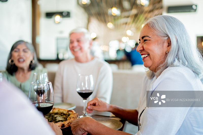 一位年长的女士在餐厅和朋友们交谈图片素材