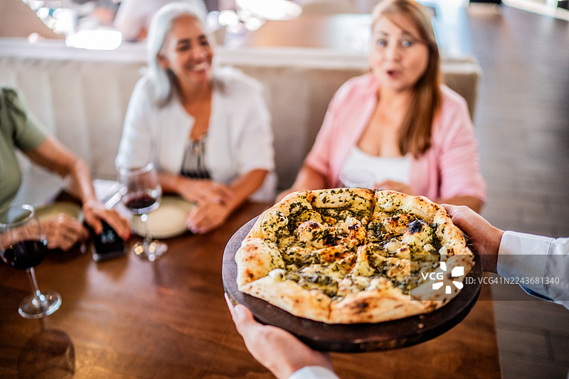餐厅里，服务员手持披萨的特写镜头图片素材