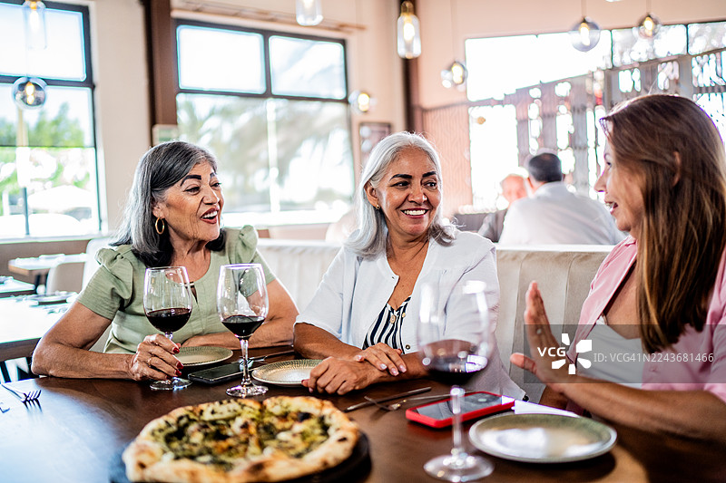 几位年长的女性朋友在餐厅边吃披萨边聊天图片素材