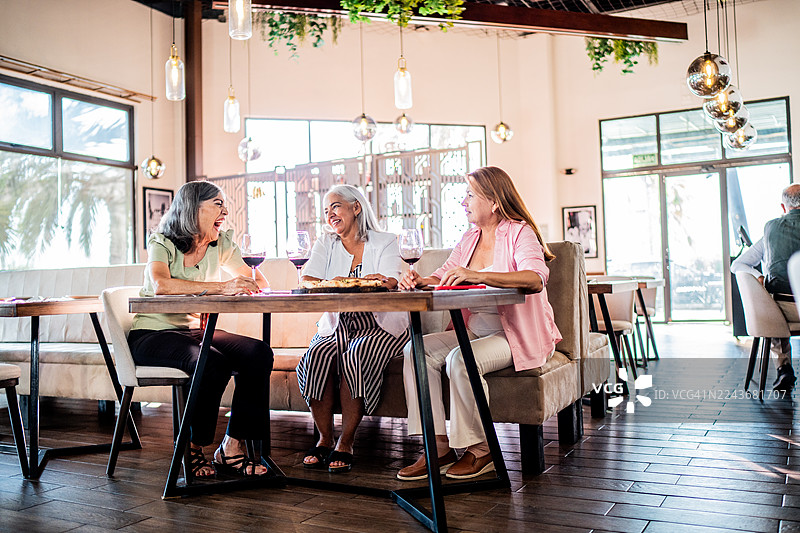 几位年长的女性朋友在餐厅边吃披萨边聊天图片素材