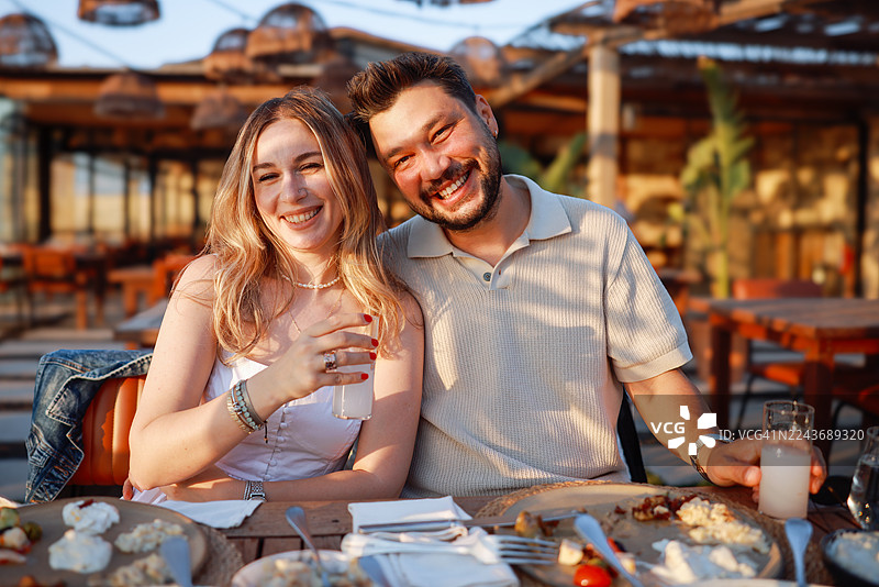年轻时尚的情侣在一家不错的餐厅里一起喝土耳其拉基，度过愉快的时光图片素材