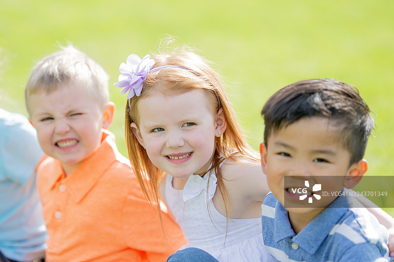 快乐的户外儿童：戴着花环的女孩在阳光明媚的田野里和朋友们一起微笑图片素材