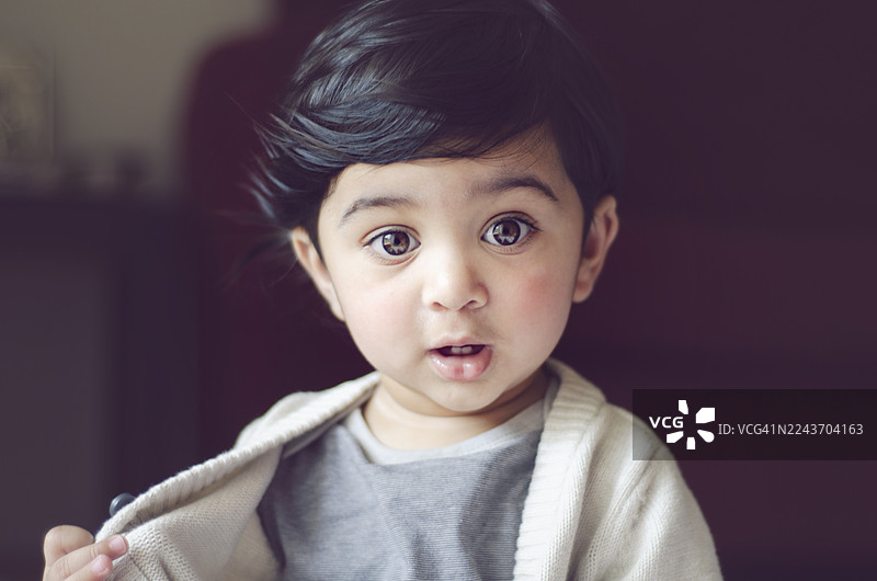 好奇的目光：一个有着大眼睛和温和表情的可爱蹒跚学步的孩子。一位印度男孩的特写肖像。图片素材