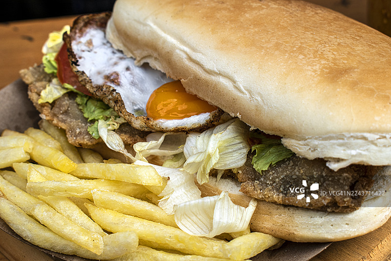 米兰炸肉排三明治，配煎蛋、番茄和生菜，以及炸薯条。阿根廷传统美食。图片素材