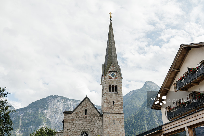 一座拥有钟表和十字架的教堂塔楼，主宰着黑利根布卢特的天际线，这是一个坐落在奥地利阿尔卑斯山的美丽村庄图片素材