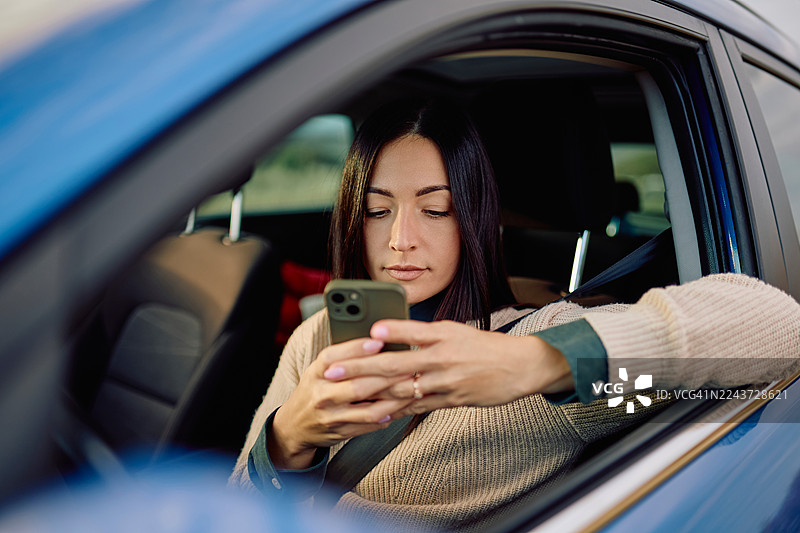 女子坐在车内用智能手机发短信图片素材
