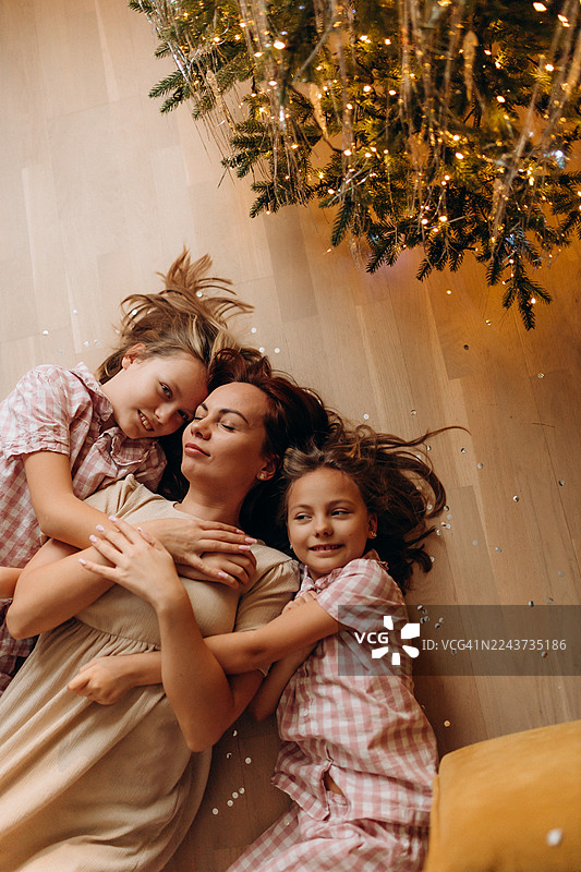 圣诞节期间，一位母亲和她的两个女儿在家里的地板上地地地图片素材