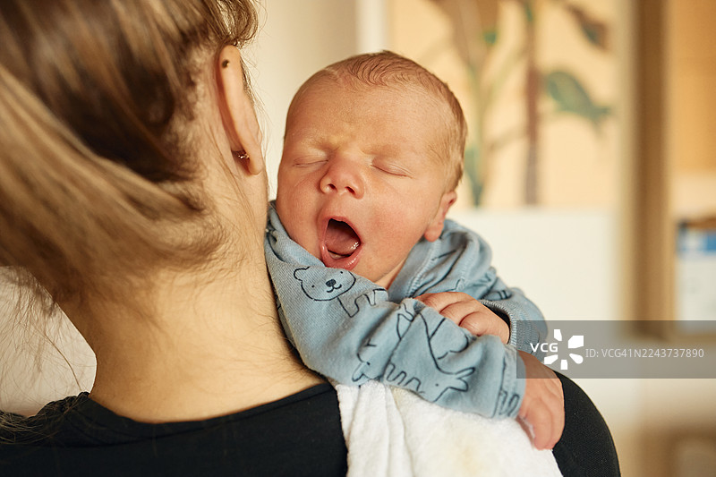 喂奶后，一位母亲抱着刚出生的婴儿打哈欠图片素材