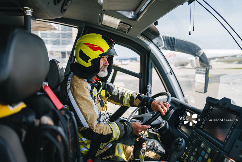 专注的成熟高加索消防员在先进的机场消防车驾驶舱内操作控制装置图片素材