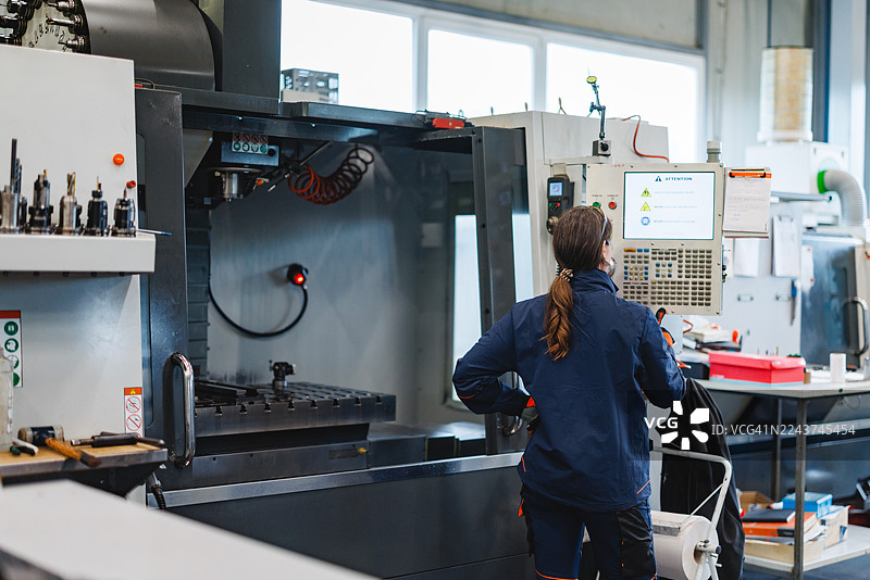 专注的中年高加索女性在车间操作先进的数控机械图片素材