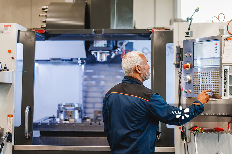 专注的技术人员在高科技工业车间操作数控机床图片素材