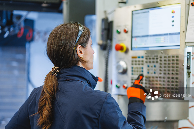 一位决心坚定的中年白人女性工程师在车间操作数控机床图片素材