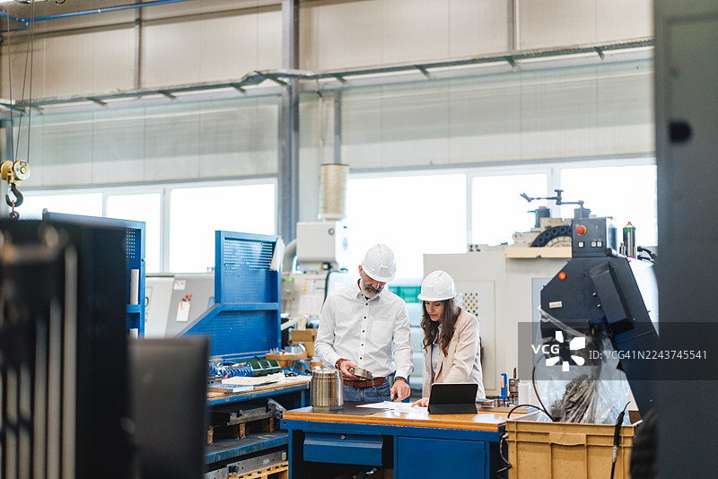敬业的中年白人工程师在工业车间分析金属部件图片素材