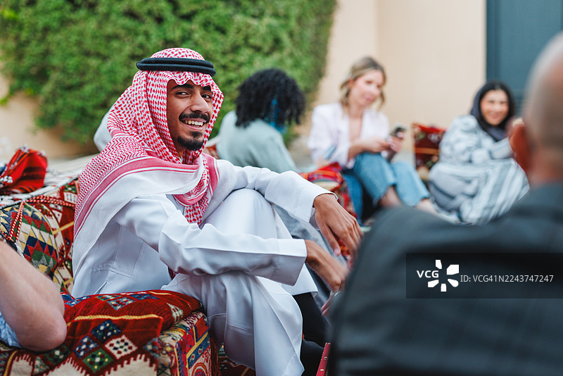 中东男性在户外马吉利斯聚会中与多元化群体互动图片素材
