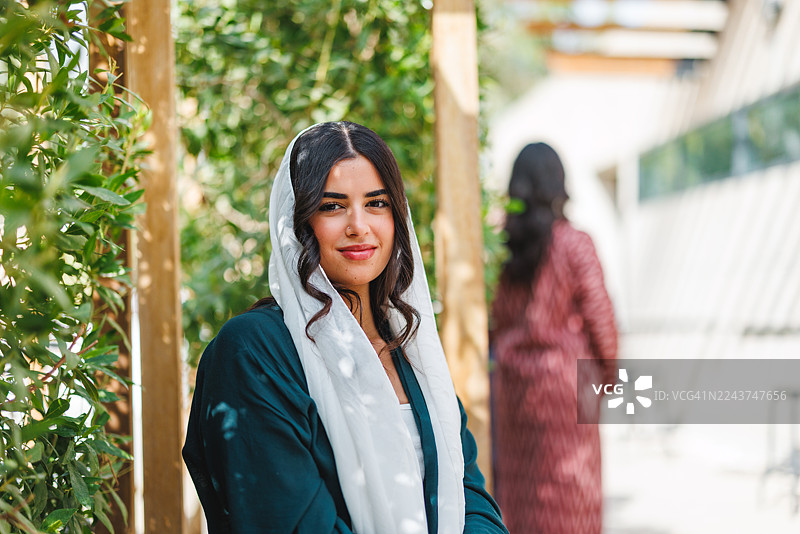 自信的中东女性，身着白色头巾和阿巴亚，享受阳光明媚的一天图片素材