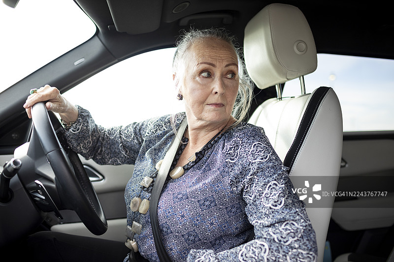 成熟的女性在倒车时回头查看图片素材