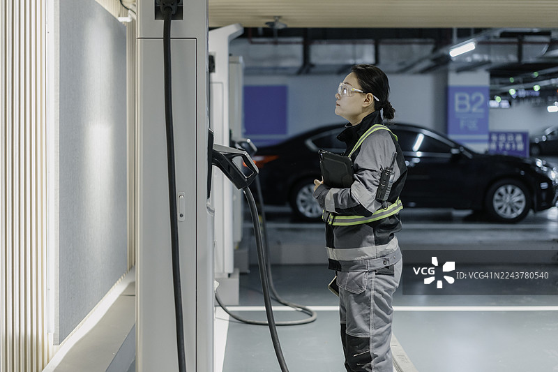 一名员工正在检查电动汽车充电站的设施。图片素材