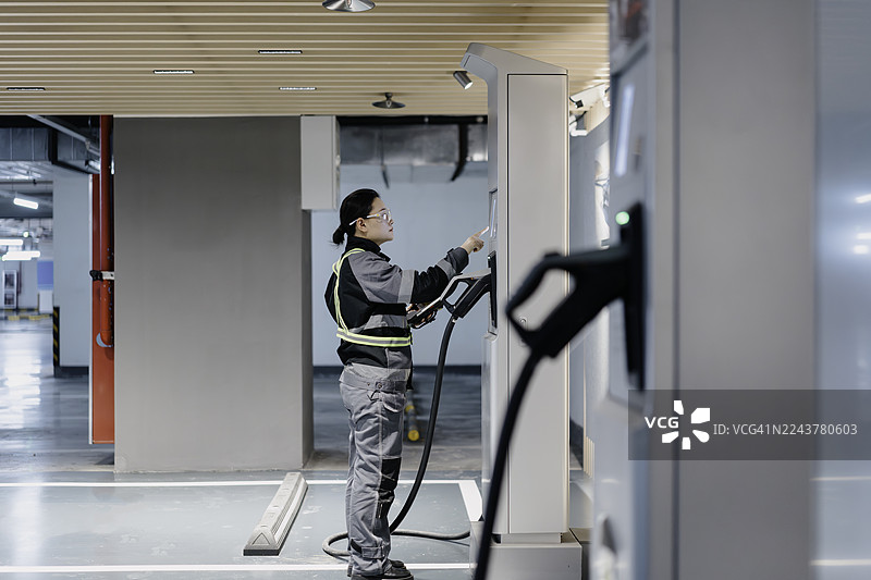 一名员工正在检查电动汽车充电站的设施。图片素材