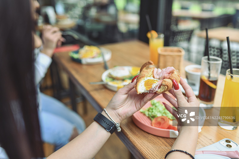 朋友们在现代酒廊酒吧享用早餐三明治，旁边还有饮品和新鲜蔬菜。图片素材