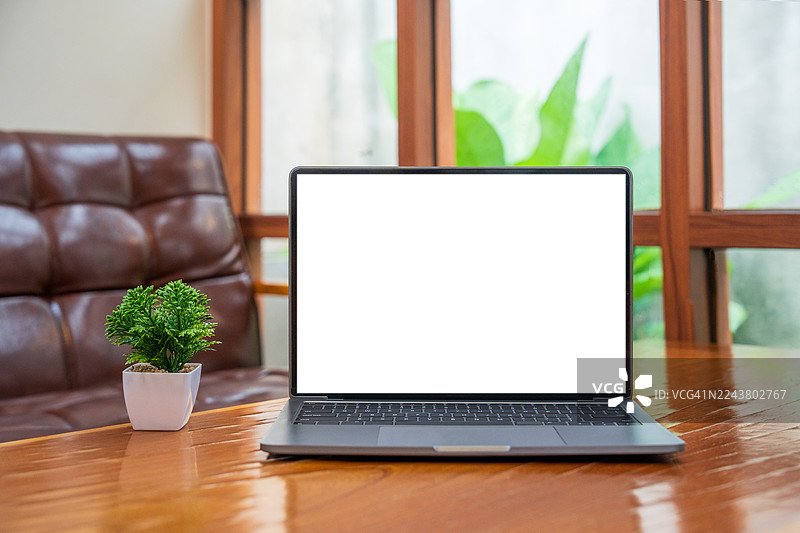 咖啡馆背景下桌子上的空白屏幕笔记本电脑。带有复制空间的笔记本电脑屏幕。舒适的工作场所。正面视图。网上冲浪。视频会议。在线购物。图片素材