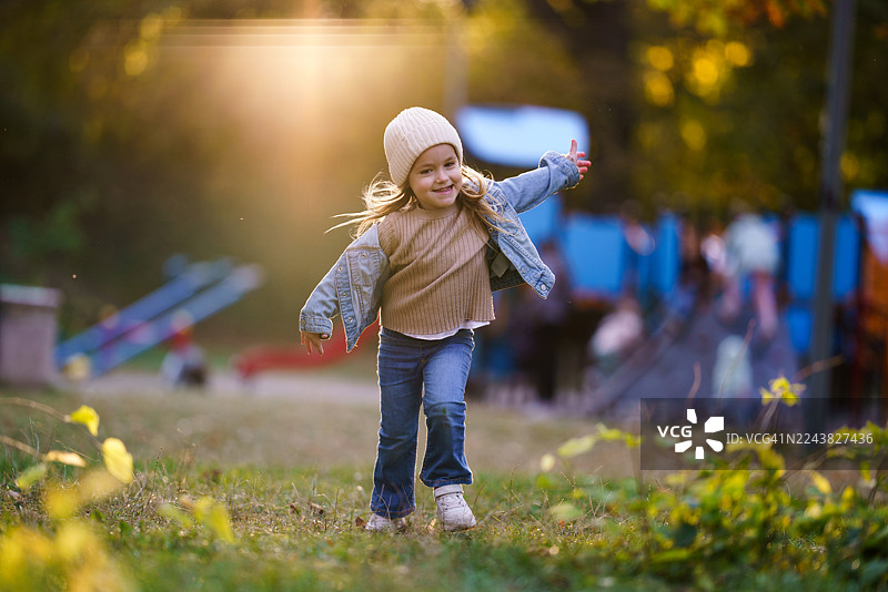 快乐的小女孩在秋日夕阳下奔跑嬉戏图片素材