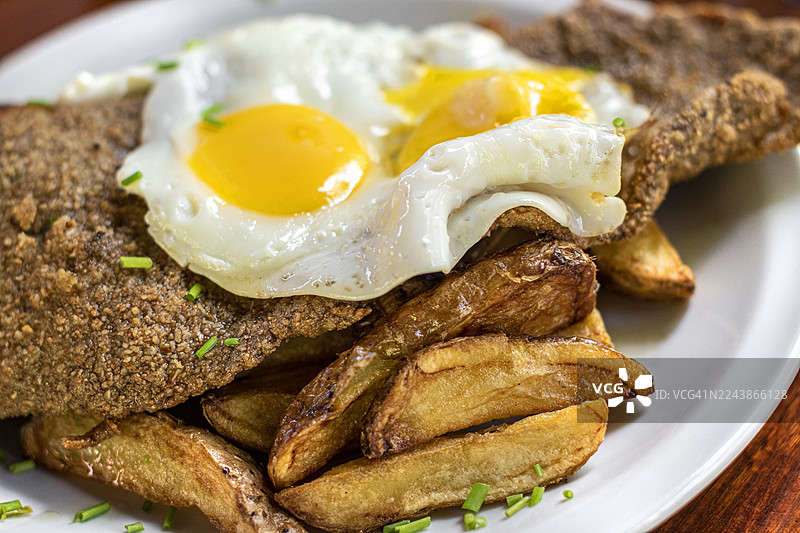 米兰萨。炸肉排配炸薯条和煎蛋。阿根廷传统美食。图片素材