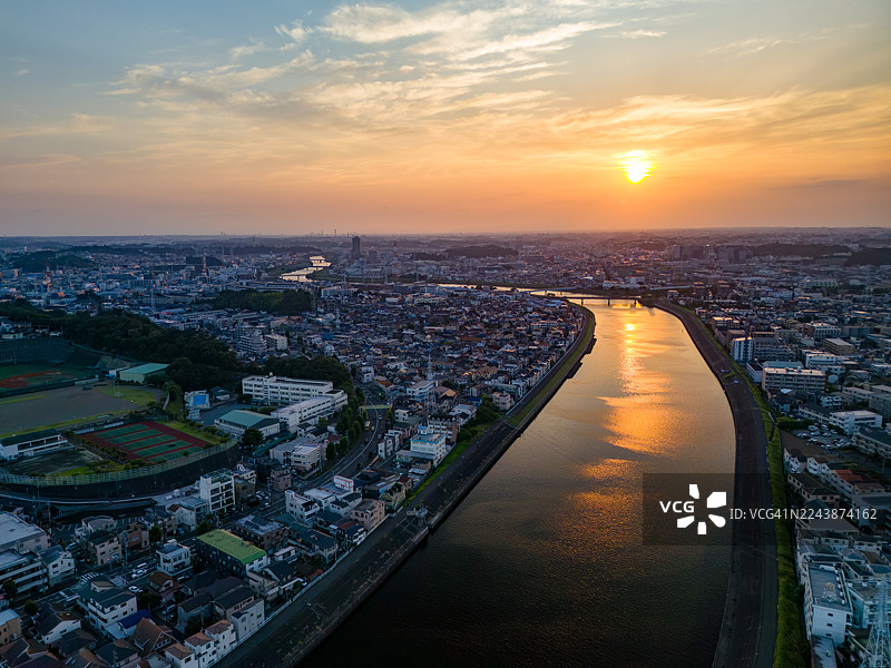 正在进行主要的桥梁更换工程。日落映照在河面上。一座横跨河流的桥梁。鹤见川的无人机航拍。西边是横滨市鹤见区；东边是川崎市川崎区和幸区。图片素材