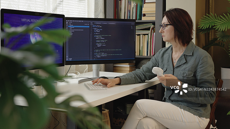 IT专家在现代办公室的双显示器上使用人工智能虚拟助手进行编码图片素材